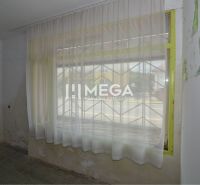 Geschäftsräume mit Vorhängen, einem Gitter am Fenster und abgenutzten Wänden.