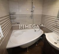 Badezimmer in einer 3-Zimmer-Wohnung mit Eckbadewanne und Boden in Holzoptik.