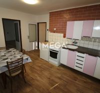 Küche in einer 2-Zimmer-Wohnung mit Holzboden, Esstisch und Schränken.