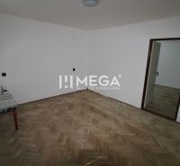Ein Zimmer in einer 2-Zimmer-Wohnung mit einem Boden in Holzoptik und einem Tisch in der Ecke.