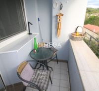 Balkon einer 2-Zimmer-Wohnung mit einem Café-Tisch und Blick ins Grüne.