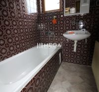 Ein Badezimmer in einem Einfamilienhaus mit braunen Fliesen und einer Badewanne.