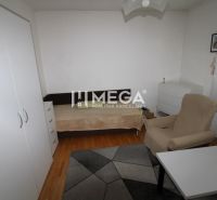 Ein Zimmer in einem Einfamilienhaus mit einem Bett, einem Sessel, einem Tisch und einem Boden mit Holzdekor.
