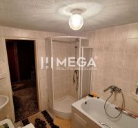Ein Badezimmer in einem Einfamilienhaus mit Badewanne, Dusche und Waschbecken, gefliest.