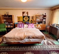 Ein Zimmer in einem Einfamilienhaus mit Bett, Teppichen, Regalen und Schreibtisch.