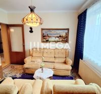 Wohnzimmer in einem Einfamilienhaus mit Sofa, Bücherregal und Vorhängen.