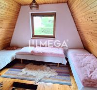 Dachzimmer in einer Hütte mit drei Betten und einem Boden in Holzoptik.