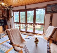 Innenraum einer Hütte mit großen Fenstern und Holzwanddekoration sowie Holzmöbeln.