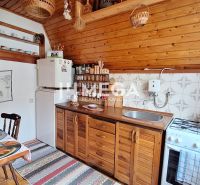 Eine Küche in einer Hütte mit einem Boden in Holzoptik, Holzschränken und einem Esstisch.