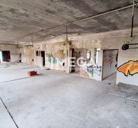 Verlassener Innenraum eines Gebäudes mit Graffiti und rohem Betonboden.
