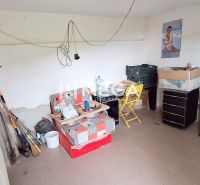 Innenraum einer Hütte mit Sessel, Stuhl, Kommode und Holzofen.