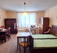 Ein Zimmer in einem Einfamilienhaus mit Holzelementen, antiken Möbeln und einfacher Beleuchtung.