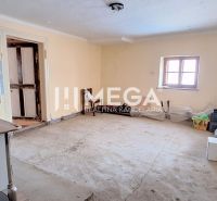 Ein Zimmer in einem Einfamilienhaus mit einem einfachen Küchenofen und einem Betonboden.