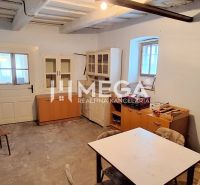 Ein Zimmer in einem Einfamilienhaus mit älteren Möbeln und einem Tisch, ohne dekorativen Bodenbelag.