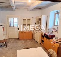 Innenraum eines Einfamilienhauses mit Holzbalkendecke, alten Türen und Möbeln.