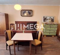 Ein Zimmer in einem Einfamilienhaus mit einem Boden in Holzoptik, einem Tisch, Stühlen und antiken Möbeln.