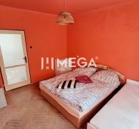 Schlafzimmer in einer 2-Zimmer-Wohnung mit orangefarbenen Wänden und einem Boden in Holzoptik.