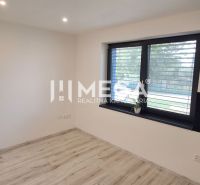 Ein Zimmer in einem Einfamilienhaus mit einem Holzboden und einem großen Fenster.