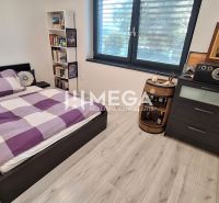 Schlafzimmer in einem Einfamilienhaus mit Bett, Regalen, Kommode und Boden mit Holzdekor.