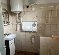 Badezimmer mit Gasheizung und Waschbecken im Einfamilienhaus, Fliesenboden, einfache Ausstattung.