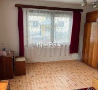 Ein Zimmer in einem Einfamilienhaus mit einem Boden in Holzoptik, roten Vorhängen und Schränken.