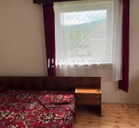 Schlafzimmer in einem Einfamilienhaus mit Bett, Fenster, roten Vorhängen und Holzboden.