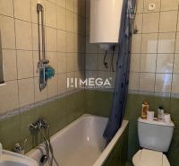Badezimmer mit Badewanne und Toilette, gefliest mit grünen Fliesen in einem Einfamilienhaus.