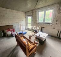 Interieur eines Einfamilienhauses mit rohen Bauwänden, einem Fenster und provisorischen Sitzgelegenheiten.