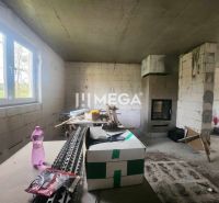 Innenraum eines Einfamilienhauses mit unvollendeten Wänden, Kamin und Baumaterial.