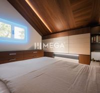 Dachbodenschlafzimmer in einem Einfamilienhaus mit Holzboden und beleuchtetem Fenster.