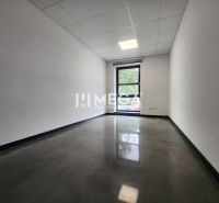 Innenraum eines Büros mit Fenster, weißen Wänden und dunklem Boden.