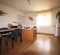 Gewerbeflächen mit Holzboden, Tisch, Stühlen und Regalen mit Büchern.
