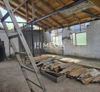 Innenraum eines Einfamilienhauses mit unfertigem Dach, Leiter und einem Haufen Holz auf dem Boden.
