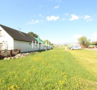 Ein Einfamilienhaus mit zwei Gebäuden und einem blühenden Rasen im Dorf Sačurov. Grundstücke - Wohnen.
