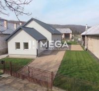 Ein Einfamilienhaus in Zbojná mit Rasen und grauem Dach zwischen zwei benachbarten Gebäuden.