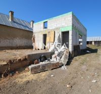 Ein Einfamilienhaus in Zbojná während des Baus mit unvollendeten Mauern und Baumaterialien.