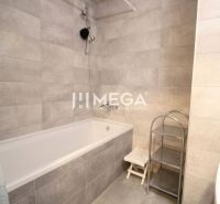 Badezimmer mit Badewanne, Dusche und Regal in einer 3-Zimmer-Wohnung, helle Fliesen.