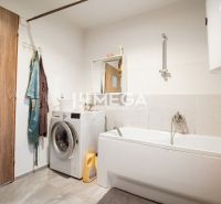 Badezimmer in einem Einfamilienhaus mit Waschmaschine, Badewanne, Spiegel und Vorhang.