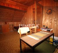 Das Innere einer Hütte mit holzverkleideten Wänden, Teppichboden und einem Tisch mit zwei Stühlen.