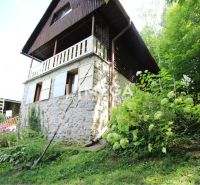 Eine Hütte in Holčíkovce mit einer Steinfassade, umgeben von Grün und Blumen.