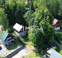 Häuser in Holčíkovce, umgeben von Wald, Gärten und einer Straße.