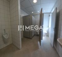 In den Büros befinden sich Toiletten mit weißen Fliesen und mehreren Kabinen.