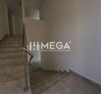 Eine Treppe in einem Büro mit gefliestem Boden und einem Fenster, das Tageslicht hereinlässt.