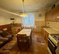 Küche in einem Einfamilienhaus mit Holzdekor auf den Stühlen und einem großen Tisch.