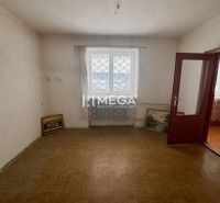 Ein Zimmer in einem Einfamilienhaus mit einem Holzboden und an die Wand gelehnten Bildern.