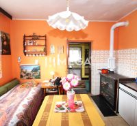 Ein Einfamilienhaus mit orangefarbenen Wänden, einem Kachelofen und Dekorationen, gemütliches Interieur.