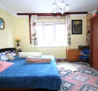 Ein Schlafzimmer in einem Einfamilienhaus mit einem blauen Bett, Holzmöbeln und einem bunten Teppich.