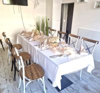 Ein gedeckter Tisch mit Dekorationen, ein Boden mit Holzdekor, Stühle in Gastronomiebereichen.