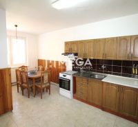 Küche in einem Einfamilienhaus mit Esstisch, Holzschränken und Fliesenboden.