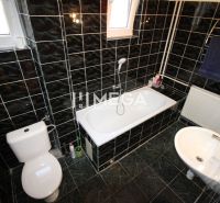 Ein Badezimmer mit dunklen Fliesen und einer Badewanne in einem Einfamilienhaus.